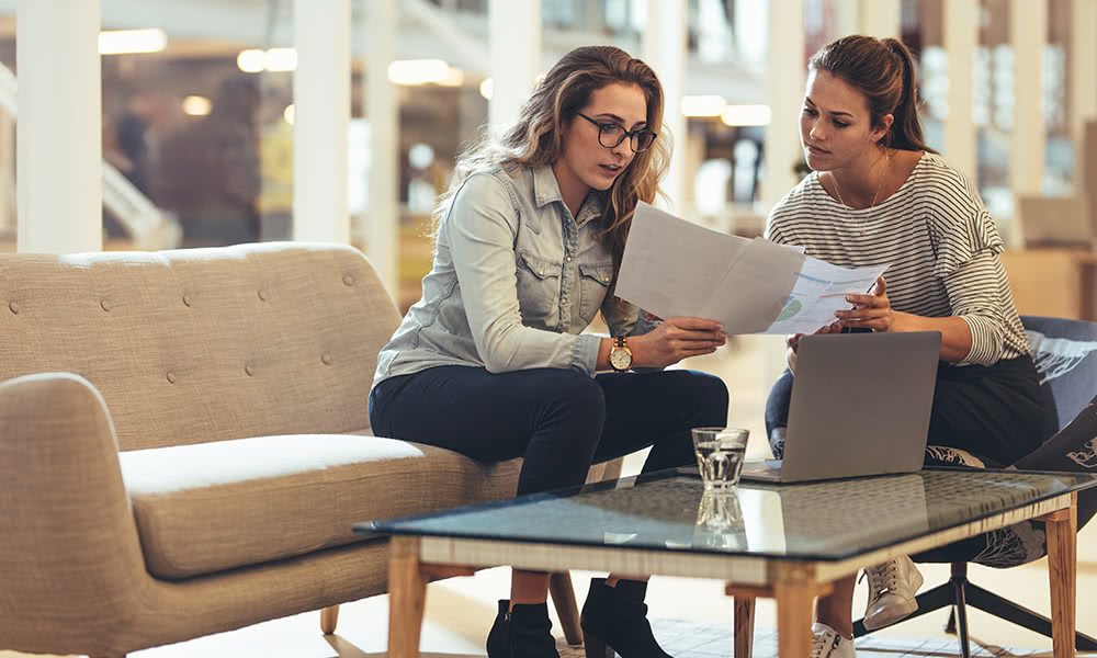 coffee-table-meeting Two Women Reviewing Documents at a Coffee Table